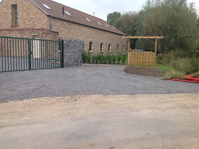 Voorzijde van de hoeve, met groen hek en grindoprit